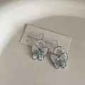 Detailed macro view of silver bow earrings with blue gradient crystals and white pearls - Pearl Crystal Butterfly Style