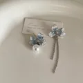 Detail of asymmetric floral earrings with blue crystal inlay, pearls, and long tassels - Asymmetric Crystal Style