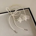 Close-up of elegant white lace flowers on a long cream string necklace with silver tips - Acrylic Flower Necklace