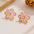Ohrringe mit rosa Marmortextur, Goldrand und Blumenform auf rustikalem Steinuntergrund - Lila