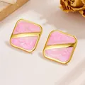 Makroaufnahme quadratischer Goldohrringe mit rosa Emaille-Marmor-Inlay - Hellviolett