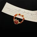 Macro detail of red carnelian bead ring with golden antler accents and beaded band - Little Dragon Ring Gold Plated