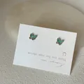 Macro detail of mini iridescent butterfly stud earrings with opal-like blue-green shimmer - Butterfly Style / Green