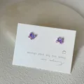 Makroaufnahme mini schillernder lila Schmetterling Ohrstecker auf Displaykarte - Schmetterlings-Stil / Lila