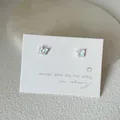 Close-up of tiny iridescent butterfly stud earrings on a white jewelry display card - Butterfly Style / White