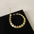 Detalle de pulsera de corazones dorados con texturas metálicas cepilladas y pulidas - Corazón / Pulsera / Dorado