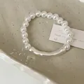 Close-up of pearl bead bracelet with silver curved tube on a minimalist ceramic tray - Pearl Bracelet / Gold