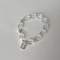 Makrodetail von klaren Kristallperlen und einem rechteckigen Metallanhänger am Armband - Ovalperlen-Tag-Stil (Stil 10)