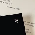 Macro shot of bow knot earring featuring pink heart zircon and small star pendant - Hollow Bowknot Heart Pendant Style (5506020064626)