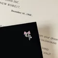 Macro detail of silver bow earring with pink heart zircon and hanging star charms - Bowknot Heart Zirconia Pendant Style (5506020064631)