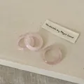 Detailed view of three faceted pink crystal resin rings on a textured beige fabric background - Rose Quartz