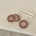 Close-up of three handmade pink natural crystal rings with polished resin texture - Strawberry Quartz