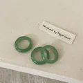 Detailed close-up of three minimalist light green crystal stone rings on a fabric texture - Green Aventurine