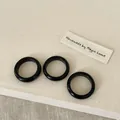 Three handmade black resin rings on textured linen fabric, minimalist smooth finish - Obsidian