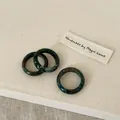 Detailed view of three polished dark green natural stone rings with unique marbled textures - Labradorite