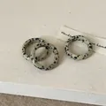 Macro detail van drie minimalistische natuurstenen ringen met spikkels op linnen stof - Dalmatijnse jaspis