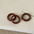 Detail van drie minimalistische roodbruine agaatstenen ringen op linnen stof - Rhodoniet
