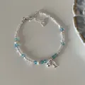 Detailed shot of silver fish bracelet with blue crystals and pearls on grey background - Little Fish Ball Style
