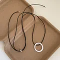 Close-up of geometric brushed metal ring pendant on adjustable black cord necklace - Round Pendant