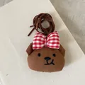Détail d'un pendentif ours en peluche marron avec nœud à carreaux rouge et broderie - Ours Marron à Bouche Torve