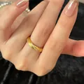 Close-up of golden twisted zircon ring with brushed metal texture on a finger - Real Gold Plated Metal / Gold