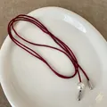 Detail van donkerrode koord choker met een witte parel en zilveren hangers eraan - Parel Strik Rode Touw Ketting