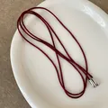 Detailopname van de wijnrode koordketting met zilveren druppelvormige metalen uiteinden - Eenvoudige Strik Rode Touw Ketting