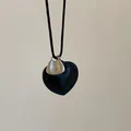 Macro view of black heart pendant with Take It Easy engraved silver metal plaque - Black Leather Heart Necklace