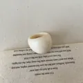 Close-up of minimalist cream resin dome ring on a textured linen background - Ring / Cream