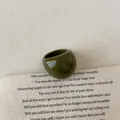 Detailed close-up of an olive green chunky resin ring on a vintage fabric background - Ring (3094)