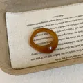 Macro detail of amber resin ring with irregular geometric design on vintage fabric - Brown Ring