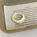 Detail view of a thick cream resin ring with brown marble patterns on linen fabric - Off-White Ring