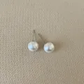 Detailed view of elegant round white pearl earrings with silver posts on textured base - Round Pearl / Mini Size (8mm)