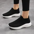 Close-up of black breathable mesh slip-on sneakers with cushioned white soles on a model - EU 36 / Black and White