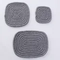 Dettaglio di tre sottobicchieri in cotone intrecciato grigio resistenti al calore su bianco - grigio scuro