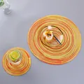 Set of round woven cotton table mats in orange and yellow spiral patterns on grey surface - Yellow Space-Dyed