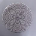 Detailaufnahme eines runden gewebten Tischsets mit grauem und beige Spiralmuster - Mittlere Ovale Form / Hellgrau