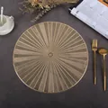 Detail of round gold PVC placemat with geometric cutouts on grey stone surface - Kaleidoscope (Gold)