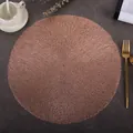 Close-up of rose gold round hollow placemat on a dark textured dining table - Alice (Rose Gold)
