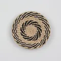 Detailed view of woven seagrass wall decor featuring a black spiral pattern on light grey background - A13