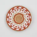 Macro shot of circular woven wall decor featuring orange and white spiral ethnic patterns - A17