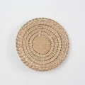 Detailed close-up of handmade woven round straw wall decor with spiral pattern - A10