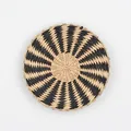 Handwoven circular wall decor with a black and beige spiral pattern in natural fiber - A22