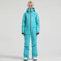 Women's turquoise one-piece ski suit with red contrast zippers and white snow boots - XS / Top And Bottom / Lake Blue