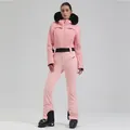 Women's pink one-piece ski suit featuring a black faux fur collar and adjustable belt - Pink