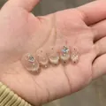 Dettaglio di cinque unghie finte rosa nude effetto cat-eye con strass argentati - XS