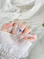 Detalle de uñas largas puntiagudas cat-eye con gema de corazón azul y diamantes de imitación - XS / Wuli Tanhua Almendra