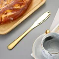 Couteau à beurre doré en acier inoxydable avec bord dentelé dans un décor de luxe - Or