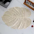 Gouden monstera blad PVC placemat met hol ontwerp op wit marmeren oppervlak - Goud