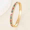 Macro detail of gold bangle featuring rainbow square gemstones and zircon side accents - Gold - Multi Color Zirconia